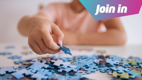 A boy holds a puzzle piece. On the table is lots of other pieces. In the top right is a graphic which says Join in