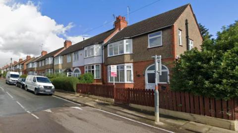 A Google Streetview image of a property on a residential road. It is an end-of-terrace house with on-street parking.