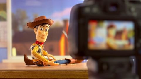 Andy from Toy Story looks to a camera inside the frame of the photo
