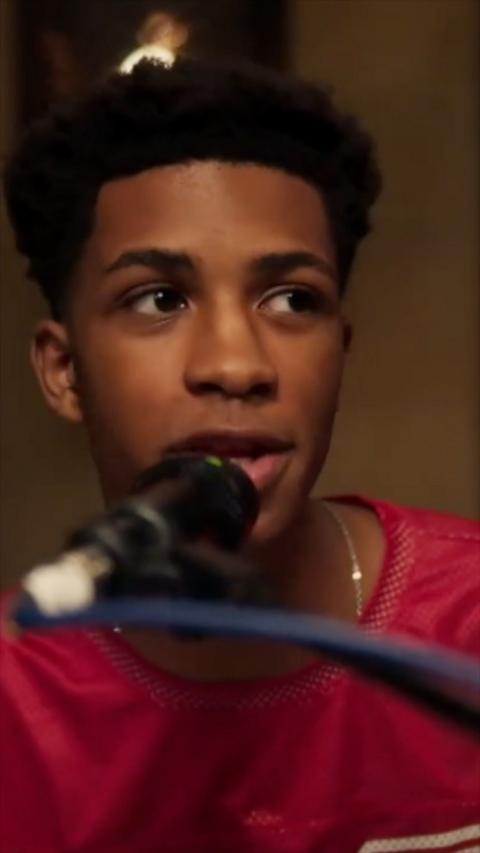 A young man with black hair singing into a microphone.