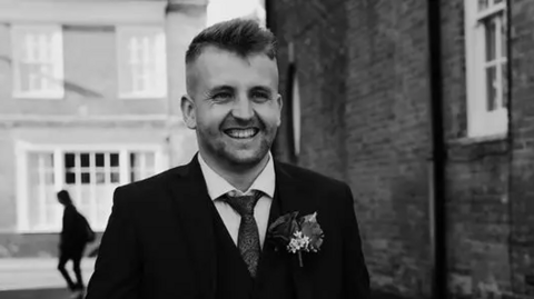 A black and white photo of Paul Ransom on his wedding day, dressed in a suit.