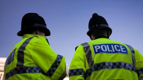 Two police officers wearing high vis jackets seen from behind