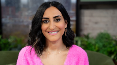 Dr Punam in the Morning Live studio, wearing a pink top, seated on a green sofa in front of some plants.