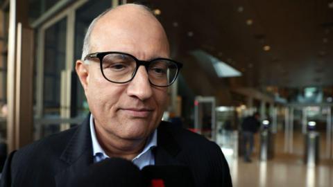 Close-up shot of Iswaran wearing black spectacles outside Singapore's court