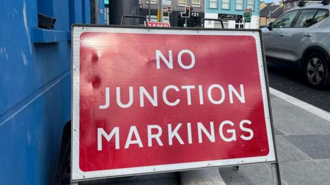 A red and white no junctions marking roadside on a pavement in Maghera.