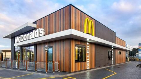 A McDonald's branded drive-thru restaurant with car lanes and a seating area.