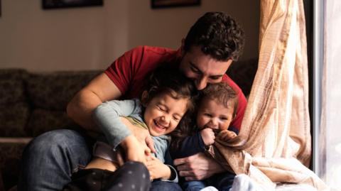 Father and two children laughing together.