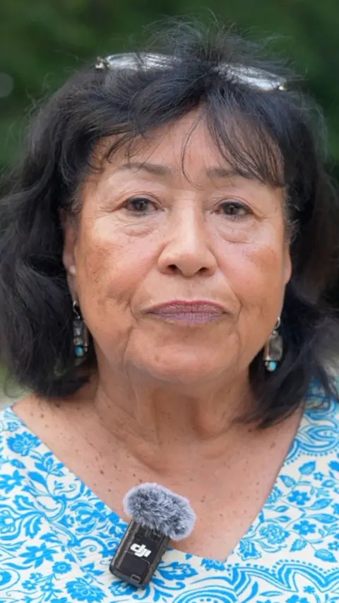 A woman looks into the camera.