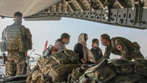 UK troops help Afghan nationals board an RAF plane in Kabul