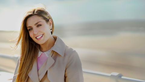 Amy Dowden in a brown jacket, looking at  the camera