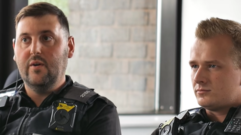 PC Oliver (left) and PC Arthur (right) in black police standard uniform. PC Oliver say short black hair with black stubble. PC Arthur is clean shaven with spikey blond hair.