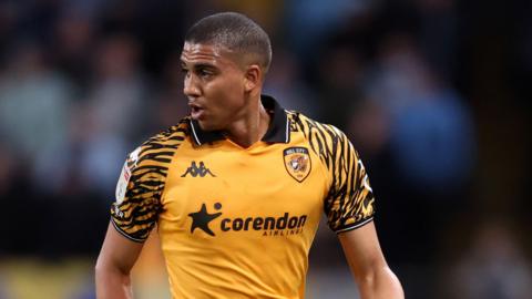 A close-up of Cody Drameh playing football in a Hull City home kit
