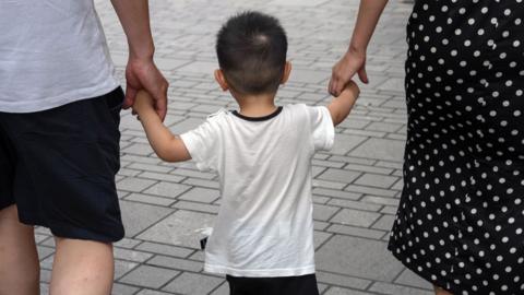 Pedestrians with a child in Beijing, China, on Sunday, July 14, 2024