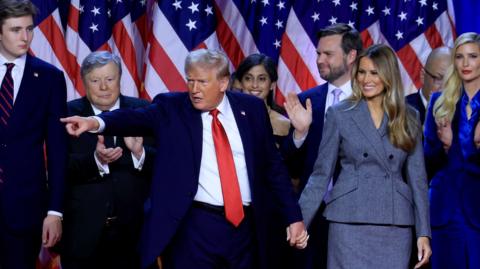 Donald Trump surrounded by friends and staff on stage after giving his victory speech