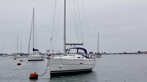 A sailing boat attached to a buoy in the harbour
