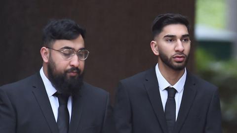 Mohammed Fahir Amaaz and Muhammad Amaad arrive at Liverpool Crown Court. Both are wearing black suits and ties.