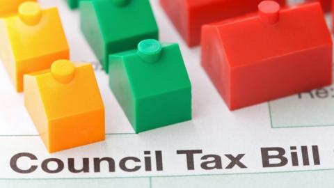 Plastic toy houses on top of a council tax bill