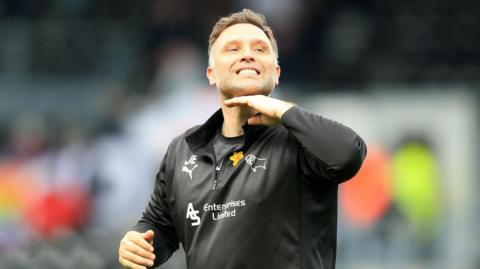 John Eustace makes 'chins up' gesture with his hand to Derby fans