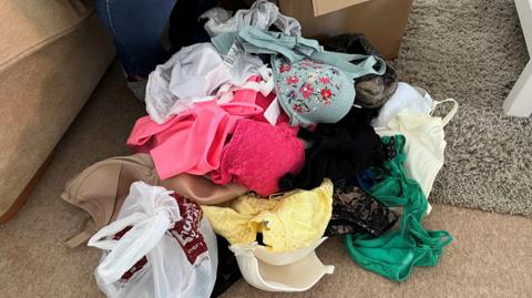 A pile of colourful bras on a beige coloured carpet.