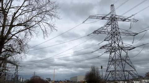 A pylon carrying overhead lines at Harker substation, Carlisle. The sky behind it is cloudy.
