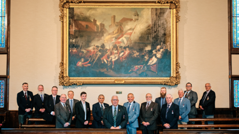 The 1781 Jersey Militia in front of the painting of the Battle of Jersey