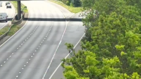 The northbound carriageway of the M5 approaching Tewkesbury. It is completely empty. The opposite carriageway has a few cars on it.
