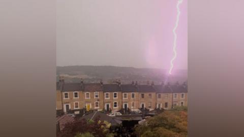 Lightning hitting hills behind houses