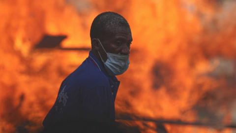 Protesters barricade a street by burning wood, tires and using iron panels as they gather at the Nation Square to stage protest against postponement of presidential election in Dakar, Senagal on February 09, 2024