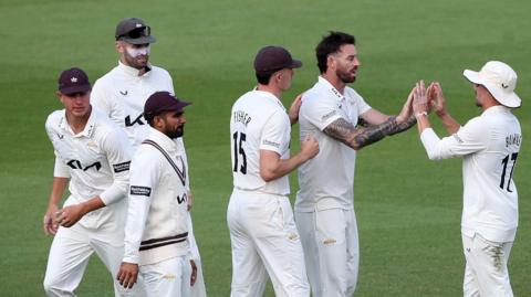 Surrey players surround Jordan Clark after a wicket