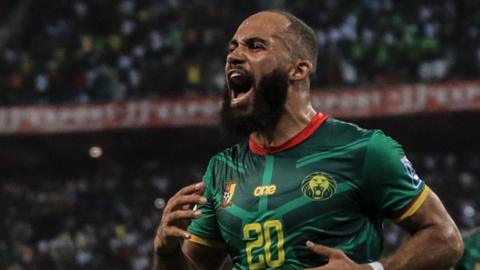 Bryan Mbeumo, wearing a green Cameroon shirt with a yellow number 20 on the chest, is seen shouting as he celebrates a goal