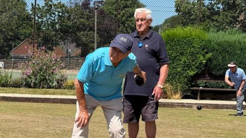 Two men taking part in a bowls match