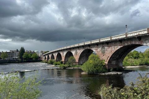 Stone bridge over a river beneath storm clouds in Perth, Perth and Kinross