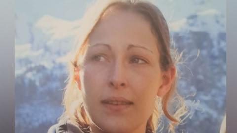 Joanna Hills, looking slightly off to the left, she has long hair, tied back, with tendrils falling around her face. She has fair hair. 