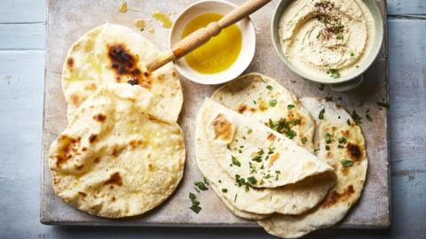 A selection of tortillas on a chopping board with a small dish of olive oil and a pastry brush
