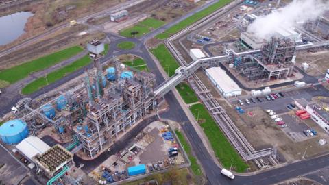 Industrial units including chimneys, scaffolding and pipework.