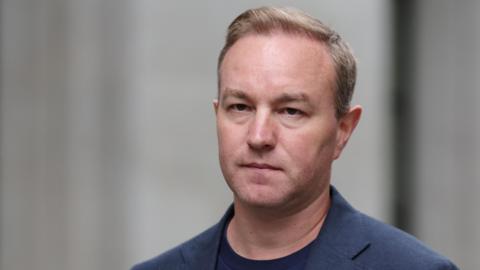 Former trader Tom Hayes arrives at the Supreme Court in London, July 2025. He is a white man with light hair. He is wearing a blue suit jacket with a blue t-shirt underneath.