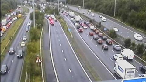 A motorway traffic camera shows a line of traffic on the M60, including on a slip road