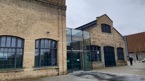 Sand Martin House is made from sand coloured brick. It has large windows and a glass entrance.