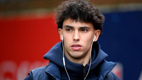 Joao Felix wears headphones and a Chelsea coat