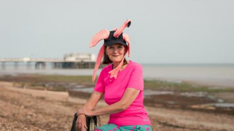 A woman in a pink outfit. She has a flamingo hat on. 