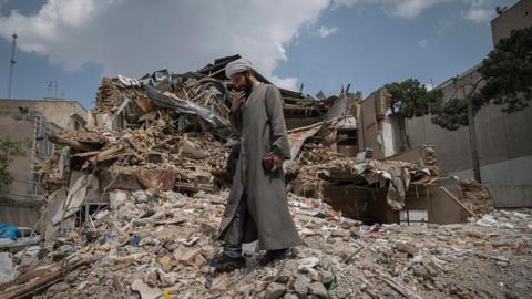 An Iranian cleric walks among the ruins of a synagogue in Tehran, Iran, on April 20, 2026.