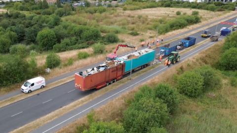 Drone shot of trailers dumped on road being emptied