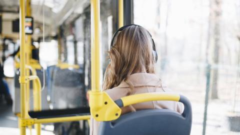 Woman listens to headphones on the bus