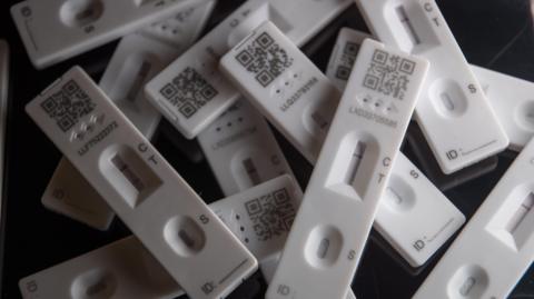 A small pile of Covid tests, stacked in haphazard fashion.