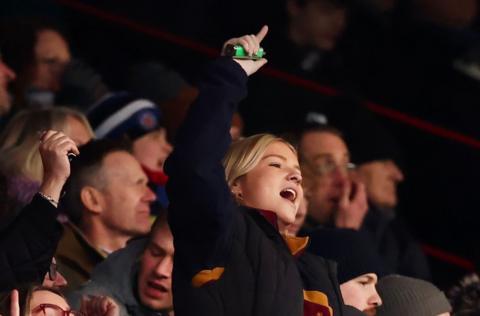 A young female fan cheers her team on, standing with a finger aloft, during the Bristol v Bath rugby game at Ashton Gate