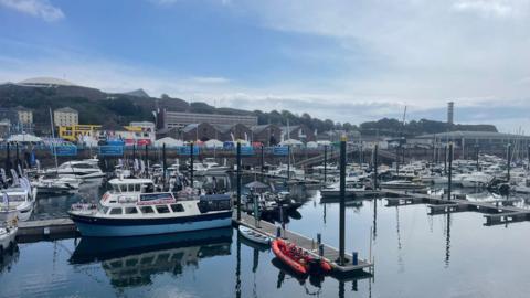 A marina full of a variety of boats in Jersey including yachts and emergency vessels. 