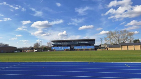 A general view picture of the Iffley Road Sports Centre in Oxford, which has a blue running track and a blue-clad sports centre in the centre of the picture. It is taken on a clear day.