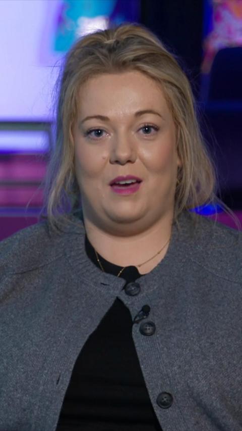 Nuala Moore has her hair tied up and is wearing a grey cardigan over a black tshirt.