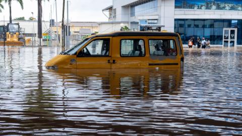 A yellow van half-submerged in floodwater
