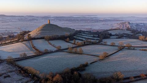 The sun rises over the Somerset Levels as frost forms on fields around Glastonbury Tor on a cold and crispy morning